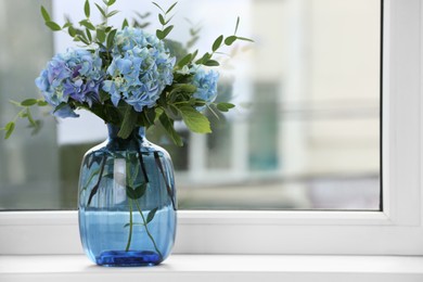 Photo of Beautiful blue hortensia flowers in vase on window sill indoors. Space for text