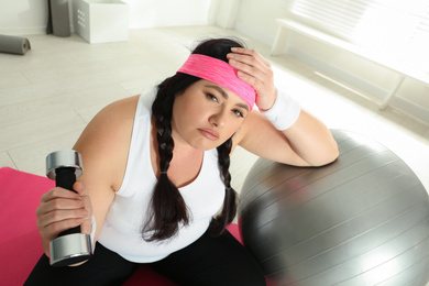 Photo of Lazy overweight woman with fit ball and dumbbell at gym