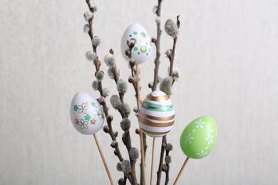 Photo of Beautiful willow branches with painted eggs on light grey background. Easter decor
