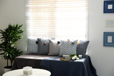 Photo of Comfortable place for rest with different cushions near window