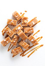 Tasty candies, caramel sauce and salt on white table, top view