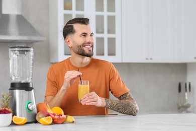 Photo of Handsome man with delicious smoothie at white marble table in kitchen