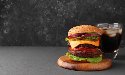 Tasty cheeseburger with patties and soda drink on grey table. Space for text