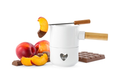 Photo of Fondue pot with chocolate and fresh peaches on white background