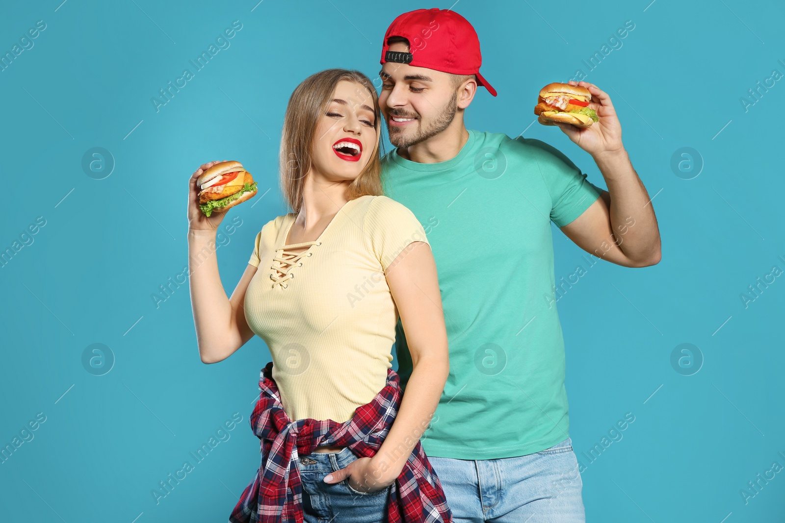 Photo of Happy couple with tasty burgers on color background