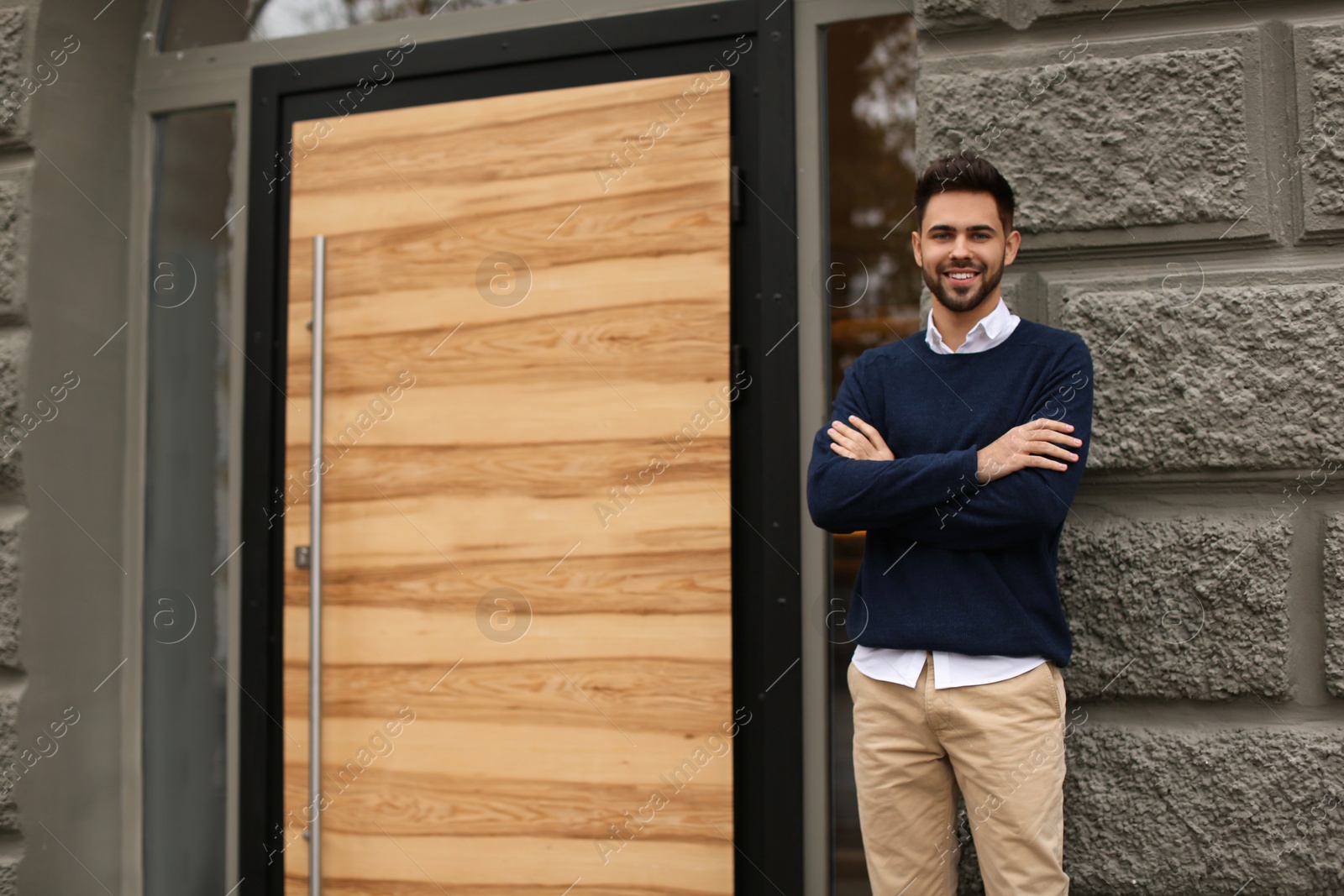 Photo of Young male business owner standing near his cafe. Space for text