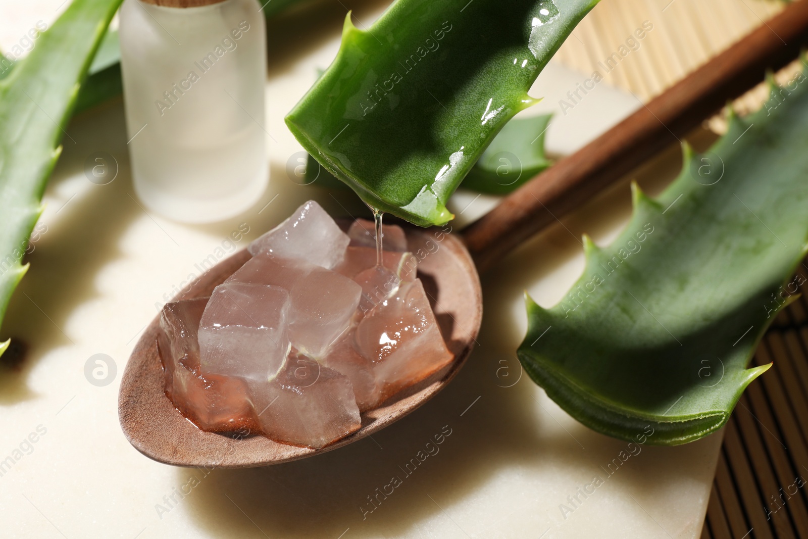 Photo of Pouring aloe vera gel from leaf into spoon at light table, closeup