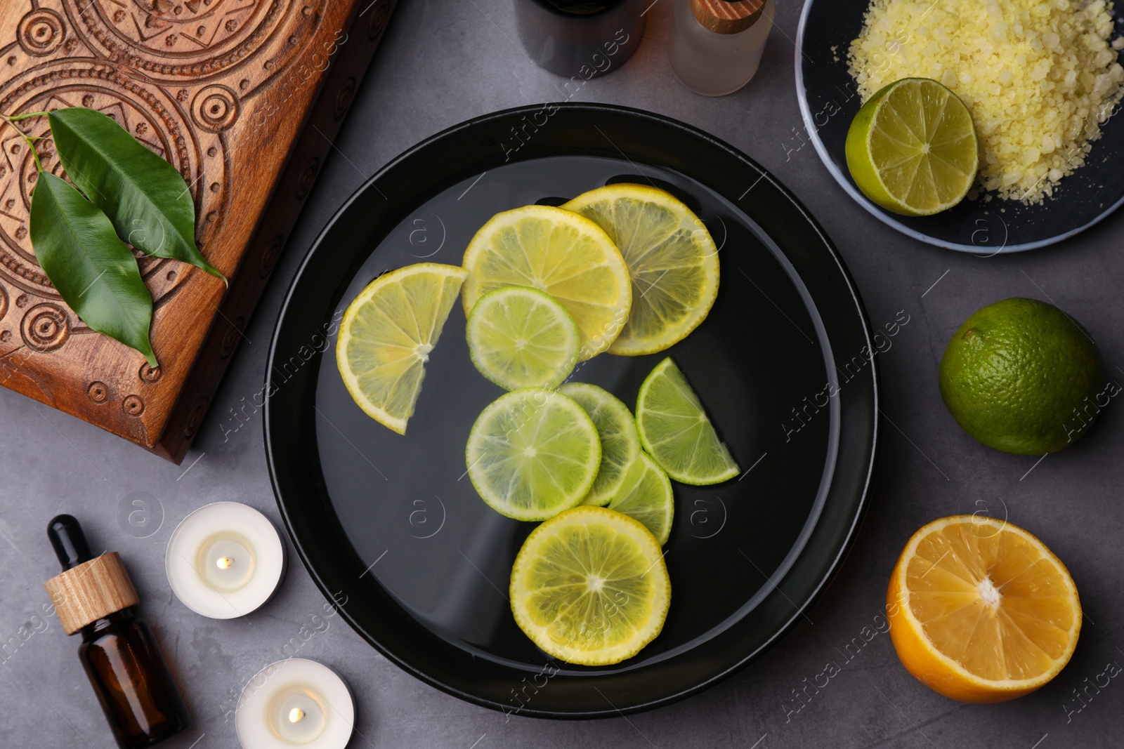 Photo of Flat lay composition with essential oil and lemons on grey table. Aromatherapy treatment