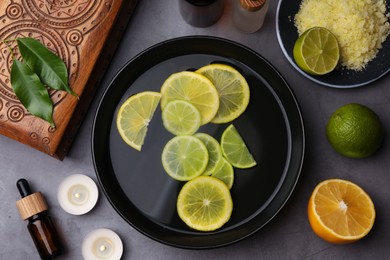 Photo of Flat lay composition with essential oil and lemons on grey table. Aromatherapy treatment