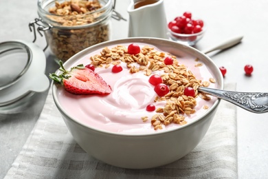 Photo of Bowl with yogurt, berries and granola on table