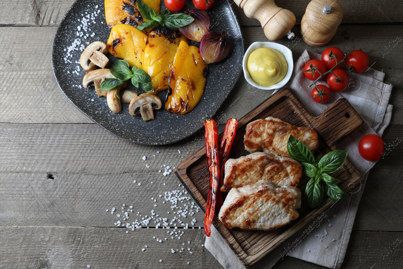 Photo of Delicious grilled meat and vegetables served on wooden table, flat lay. Space for text