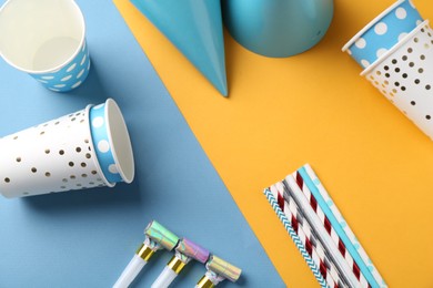 Party hats and other bright decor on color background, flat lay