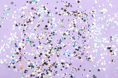 Photo of Shiny glitter on lilac background, top view