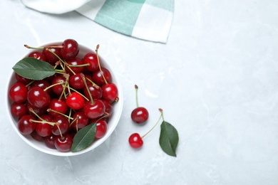 Photo of Sweet juicy cherries with leaves on grey marble table, flat lay. Space for text