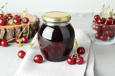 Photo of Jar of pickled cherries and fresh fruits on light table