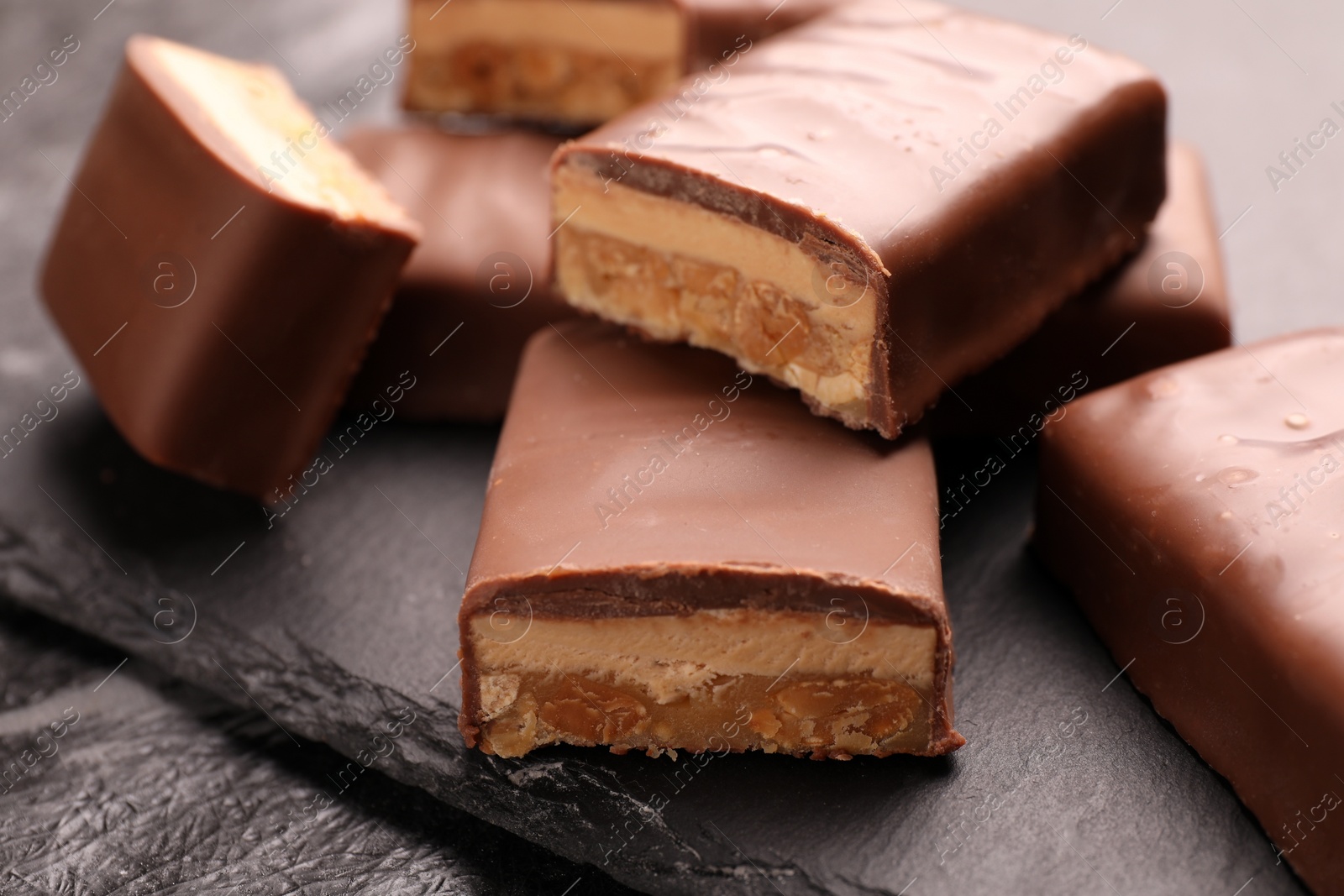 Photo of Tasty chocolate bars with nougat on gray table, closeup