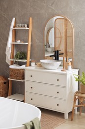 Chest of drawers with sink and beautiful green houseplants in bathroom. Interior design