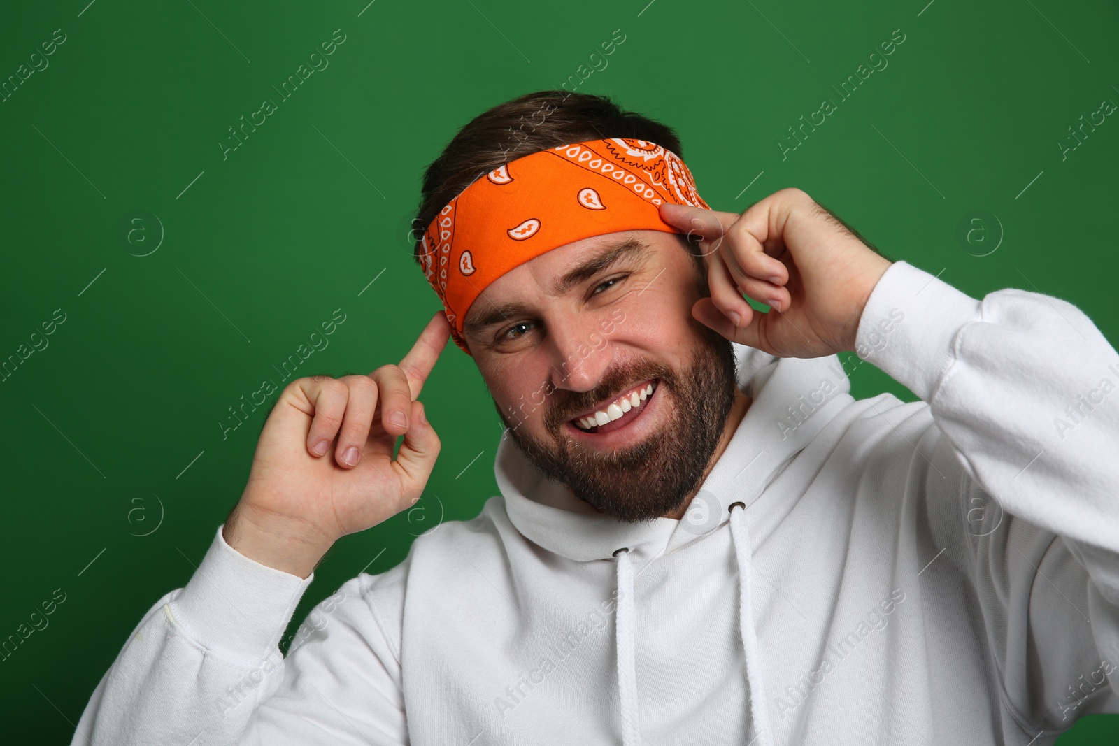 Photo of Fashionable young man in stylish outfit with bandana on green background