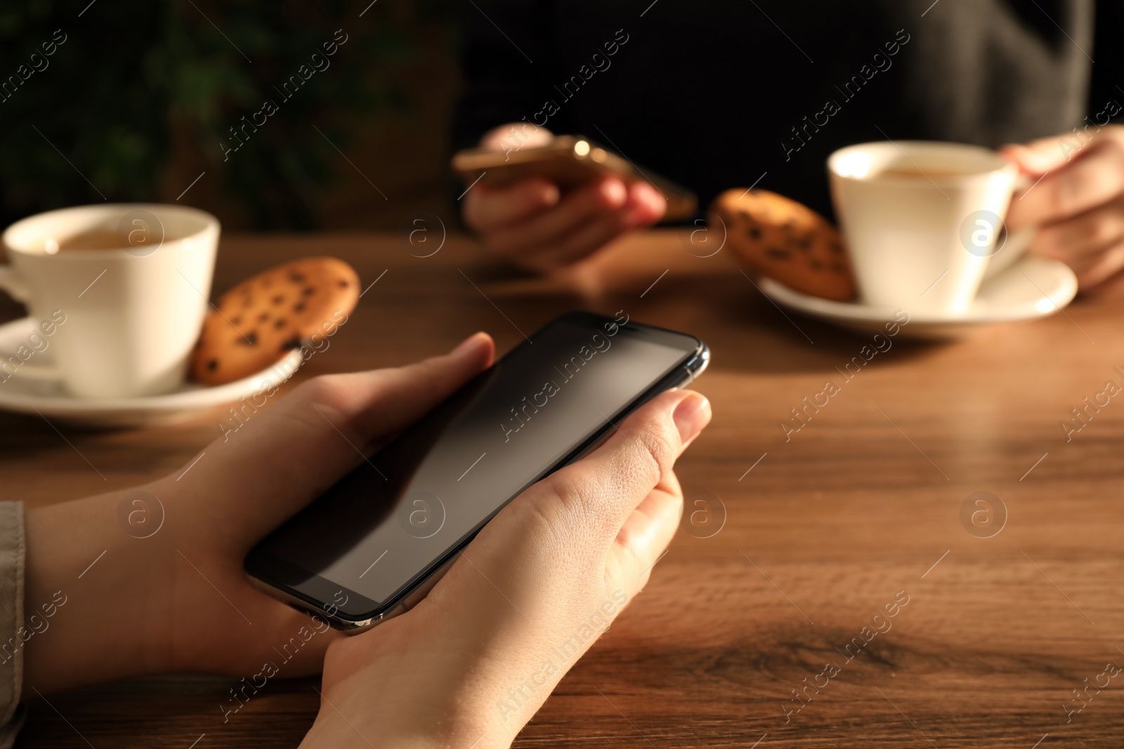 Photo of Women using mobile phones at table in cafe, closeup