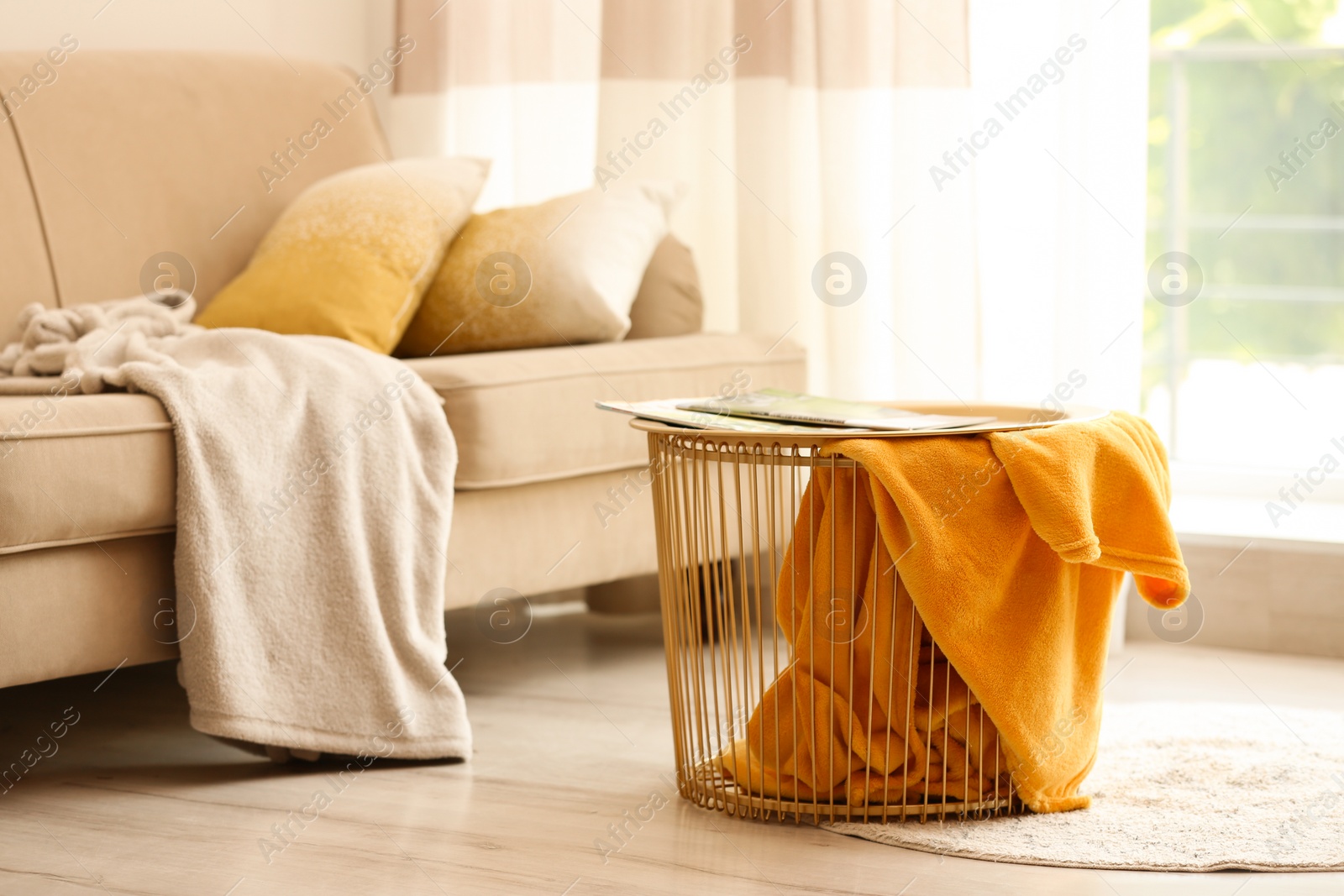 Photo of Metal basket with yellow blanket in modern room, space for text. Idea for interior design