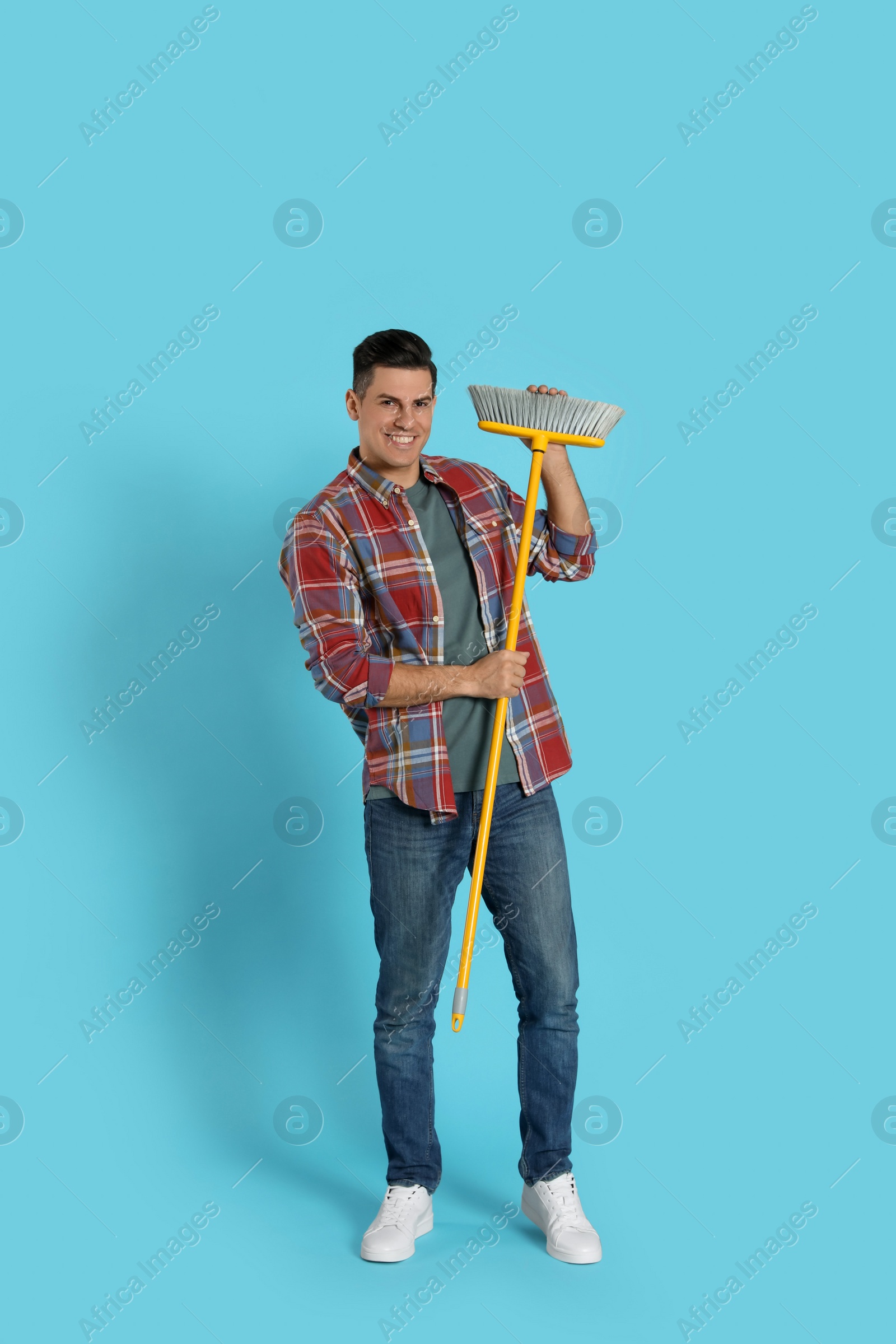 Photo of Man with yellow broom on light blue background