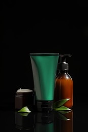 Photo of Facial cream and other men's cosmetic products on black background