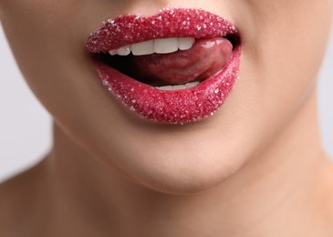 Young woman with beautiful lips covered in sugar on light background, closeup