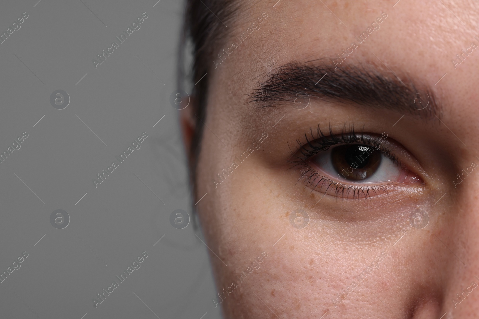Photo of Closeup view of woman with beautiful eyes on grey background, space for text