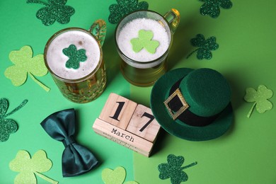 St. Patrick's day party on March 17. Green beer, leprechaun hat, bowtie, wooden block calendar and decorative clover leaves on green background, above view