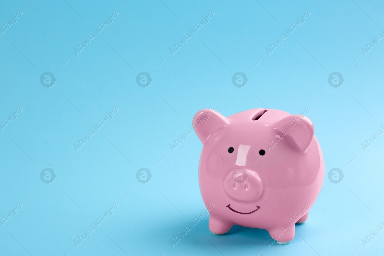 Photo of Pink piggy bank on light blue background. Space for text