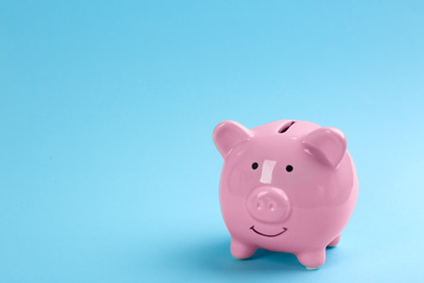 Photo of Pink piggy bank on light blue background. Space for text