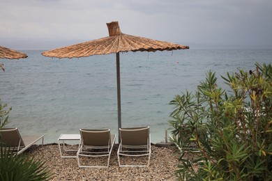 Photo of Beautiful straw umbrella and sunbeds near sea