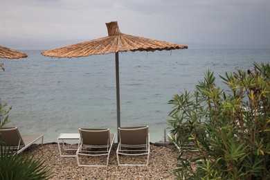 Beautiful straw umbrella and sunbeds near sea