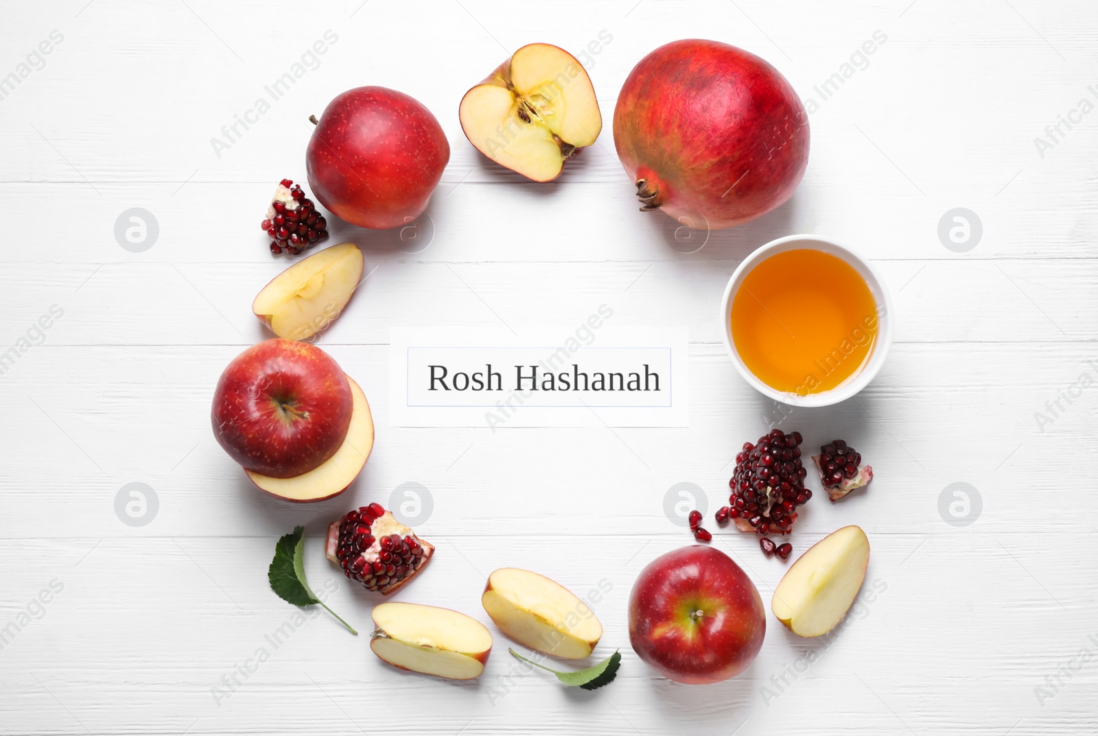 Photo of Card with text ROSH HASHANAH, apples, honey and pomegranates on white wooden table, flat lay