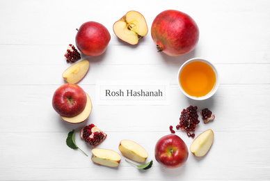 Card with text ROSH HASHANAH, apples, honey and pomegranates on white wooden table, flat lay