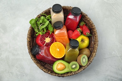 Basket with healthy detox smoothies and ingredients on light background, top view