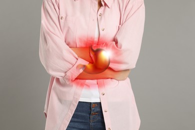 Woman suffering from abdominal pain on grey background, closeup. Illustration of unhealthy stomach