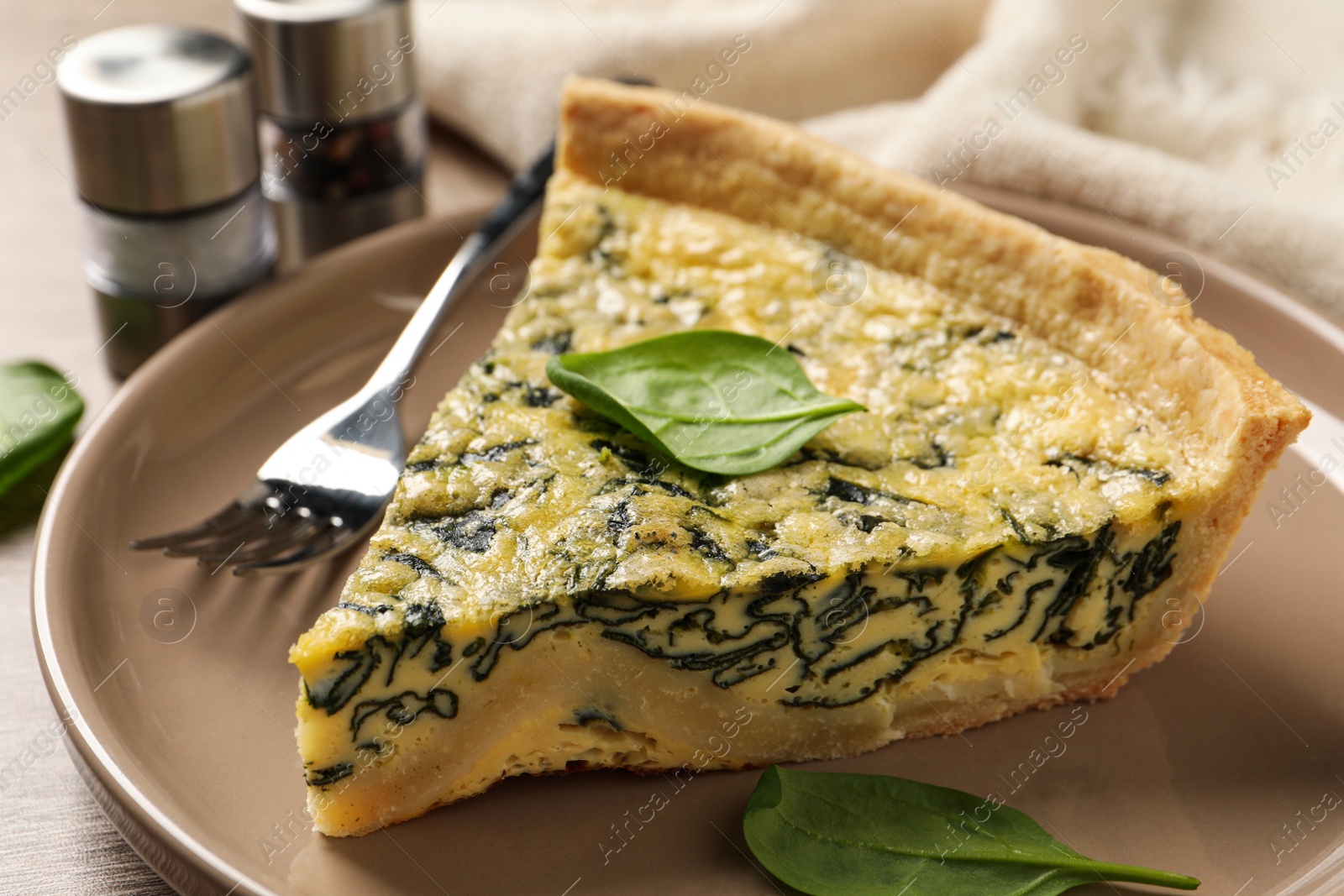 Photo of Piece of delicious homemade spinach pie and fork on plate, closeup