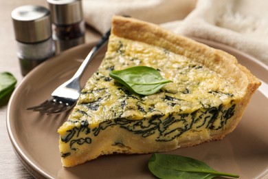 Piece of delicious homemade spinach pie and fork on plate, closeup