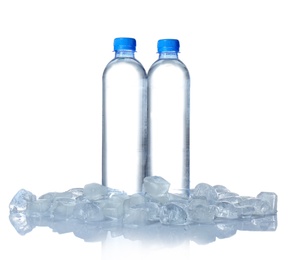 Photo of Bottles of water and ice cubes on white background