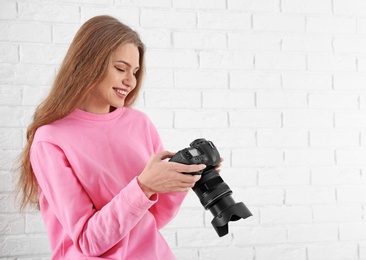 Photo of Female photographer with camera on brick background