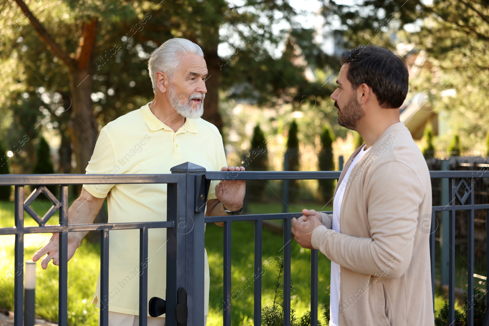 Photo of Relationship with neighbours. Men near fence outdoors