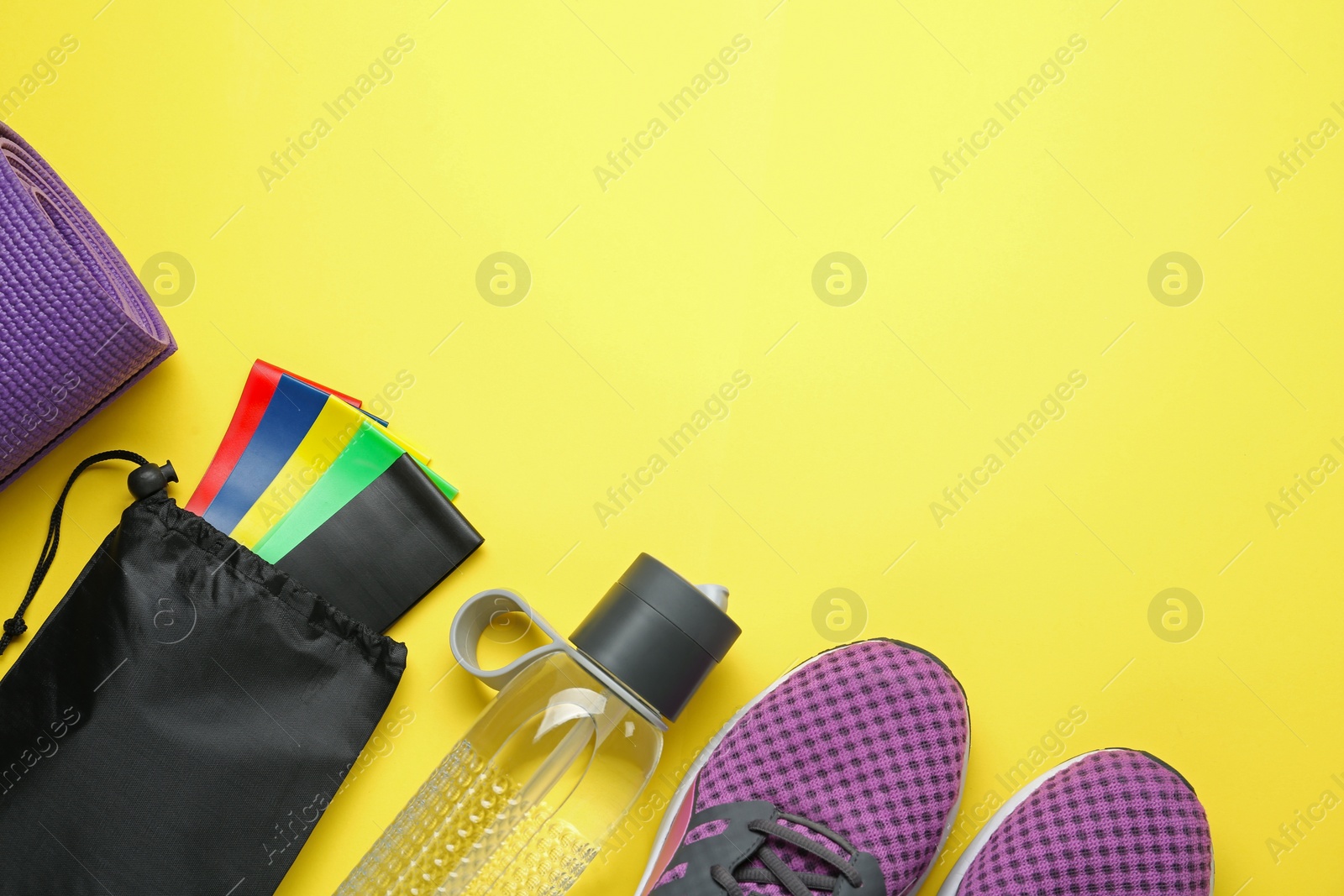 Photo of Flat lay composition with fitness elastic bands on yellow background Space for text