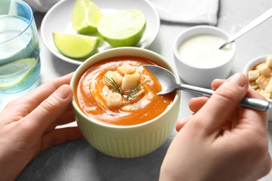 Photo of Woman eating tasty sweet potato soup at table, closeup