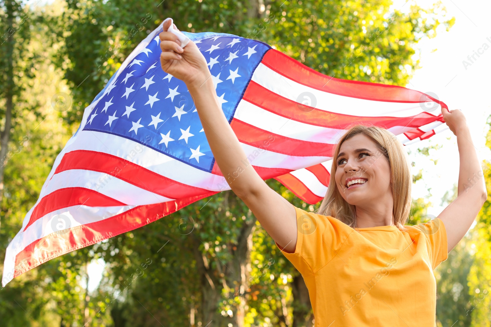 Photo of Woman with American flag in park on sunny day