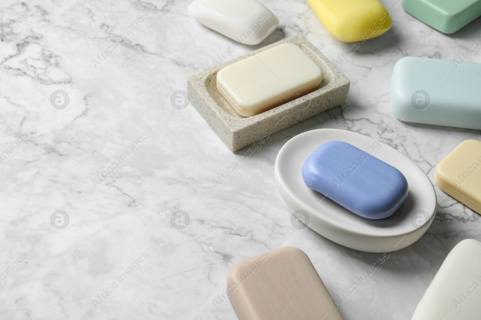 Photo of Many different soap bars on white marble table, space for text
