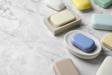 Photo of Many different soap bars on white marble table, space for text
