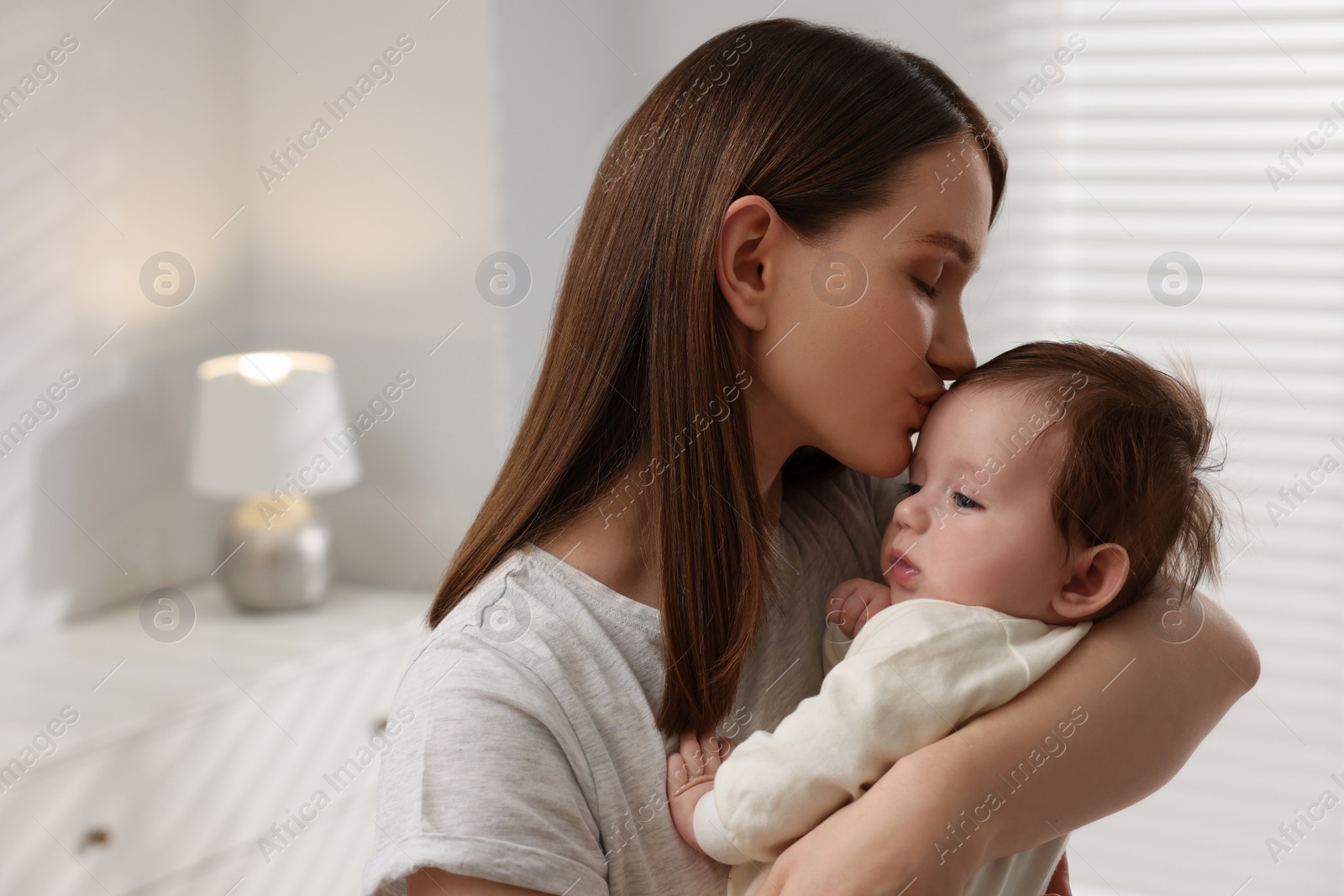 Photo of Happy mother kissing her little baby at home