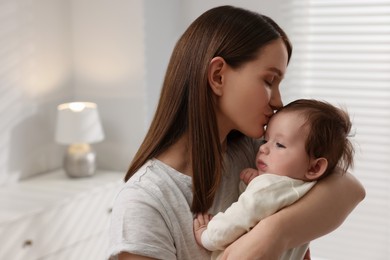 Happy mother kissing her little baby at home