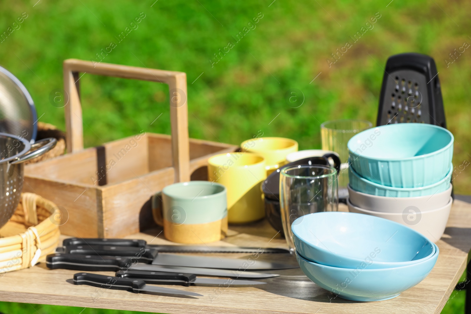 Photo of Many different items for kitchen on wooden table outdoors. Garage sale